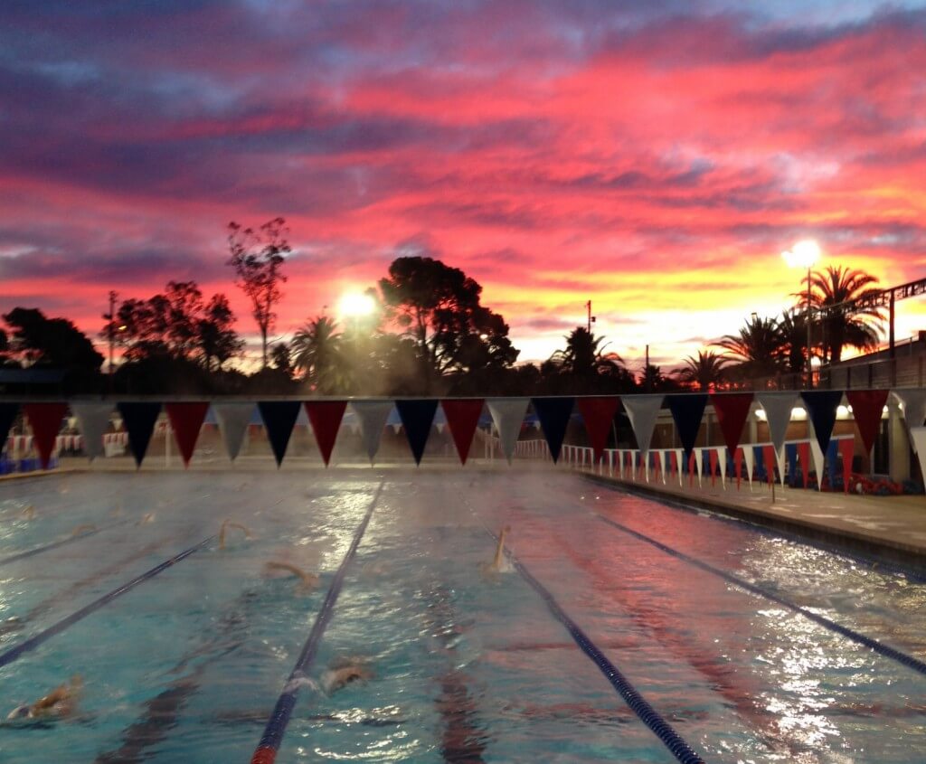 Empty indoor pool with sunlight on the water.